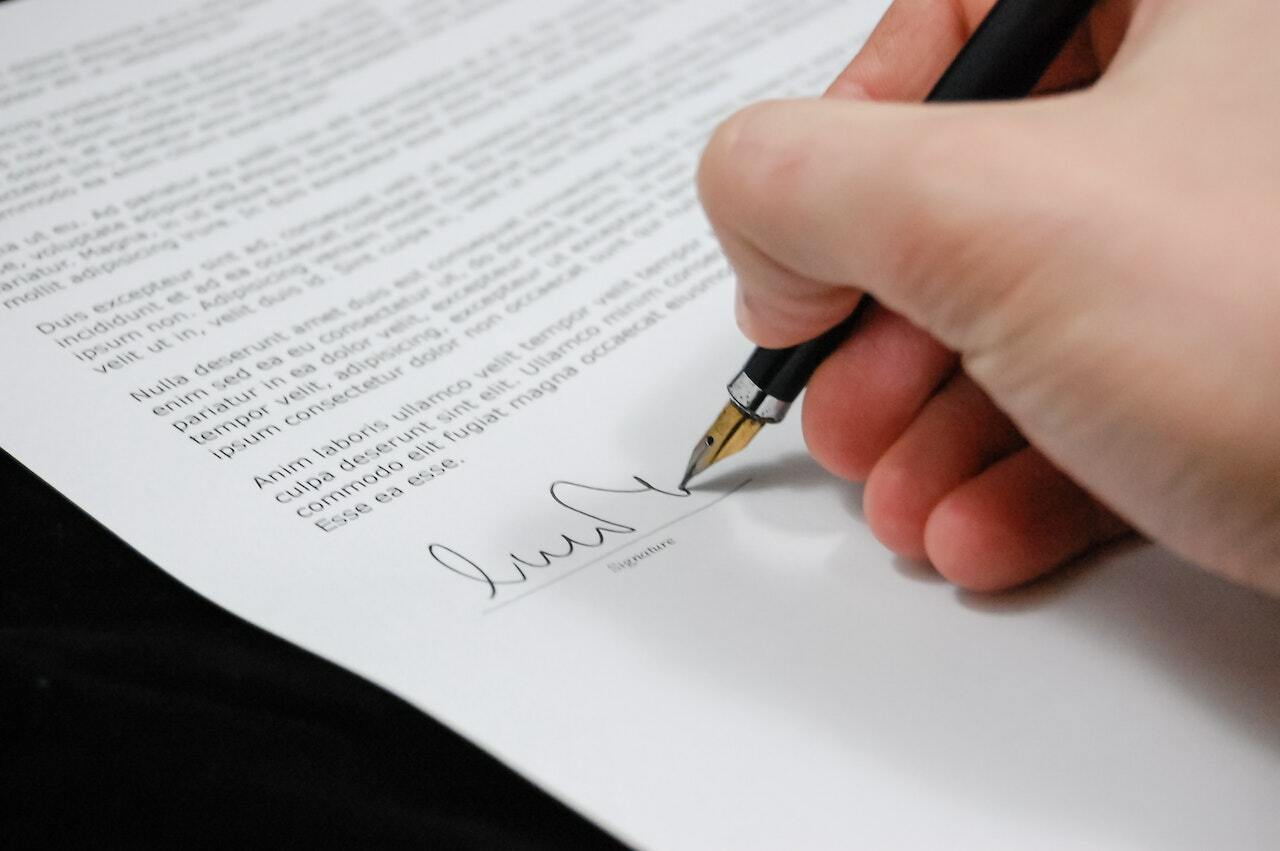 Hand with a pen signing a document